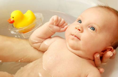 Младенца купают в ванночке