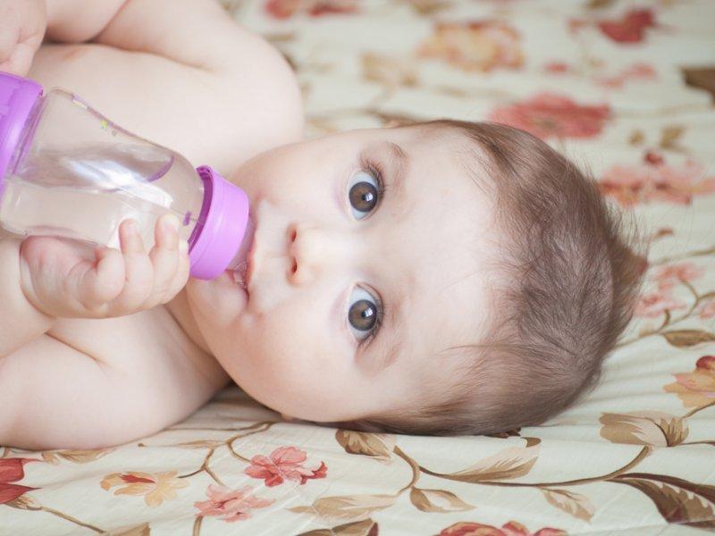 Младенец пьет укропную водичку из бутылочки