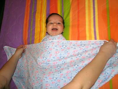 Располагаем нижнюю кромку пеленки у малыша на груди выше согнутых рук