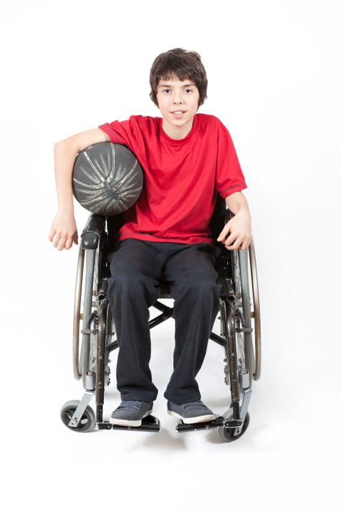 A boy in a wheelchair holding a basketball.